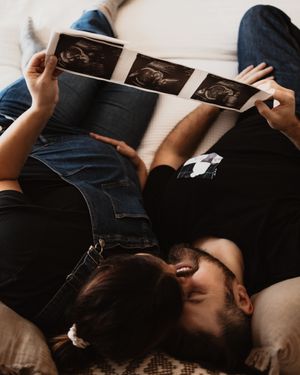 A couple lying down together looking at ultrasound photos.