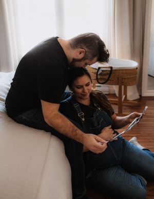 A couple shares a tender moment while looking at something on a tablet.