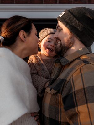 Cozy winter family moment with couple embracing child wearing knit beanie.