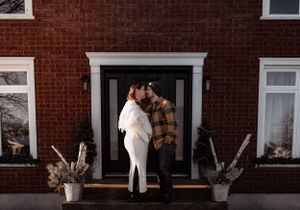 Romantic moment between couple against red brick facade with black door.