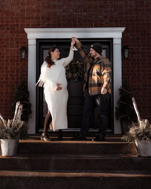 A couple dances playfully on their front porch decorated for the holidays.