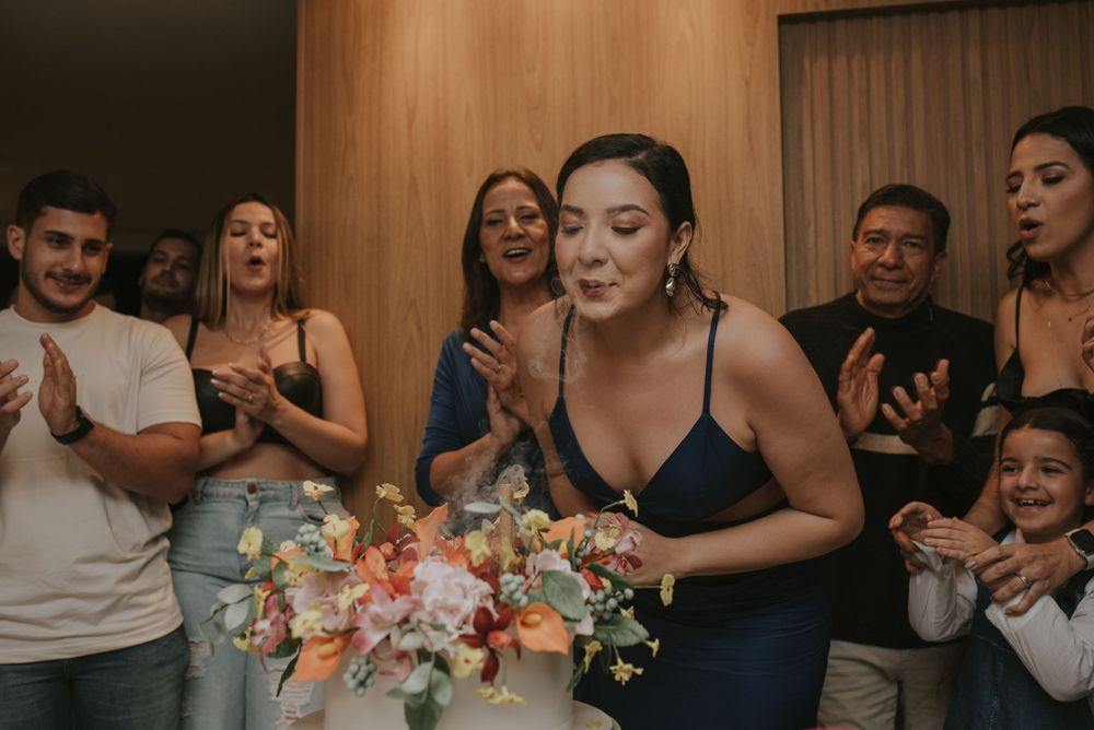 Group celebrating with cake and flowers at an intimate gathering.