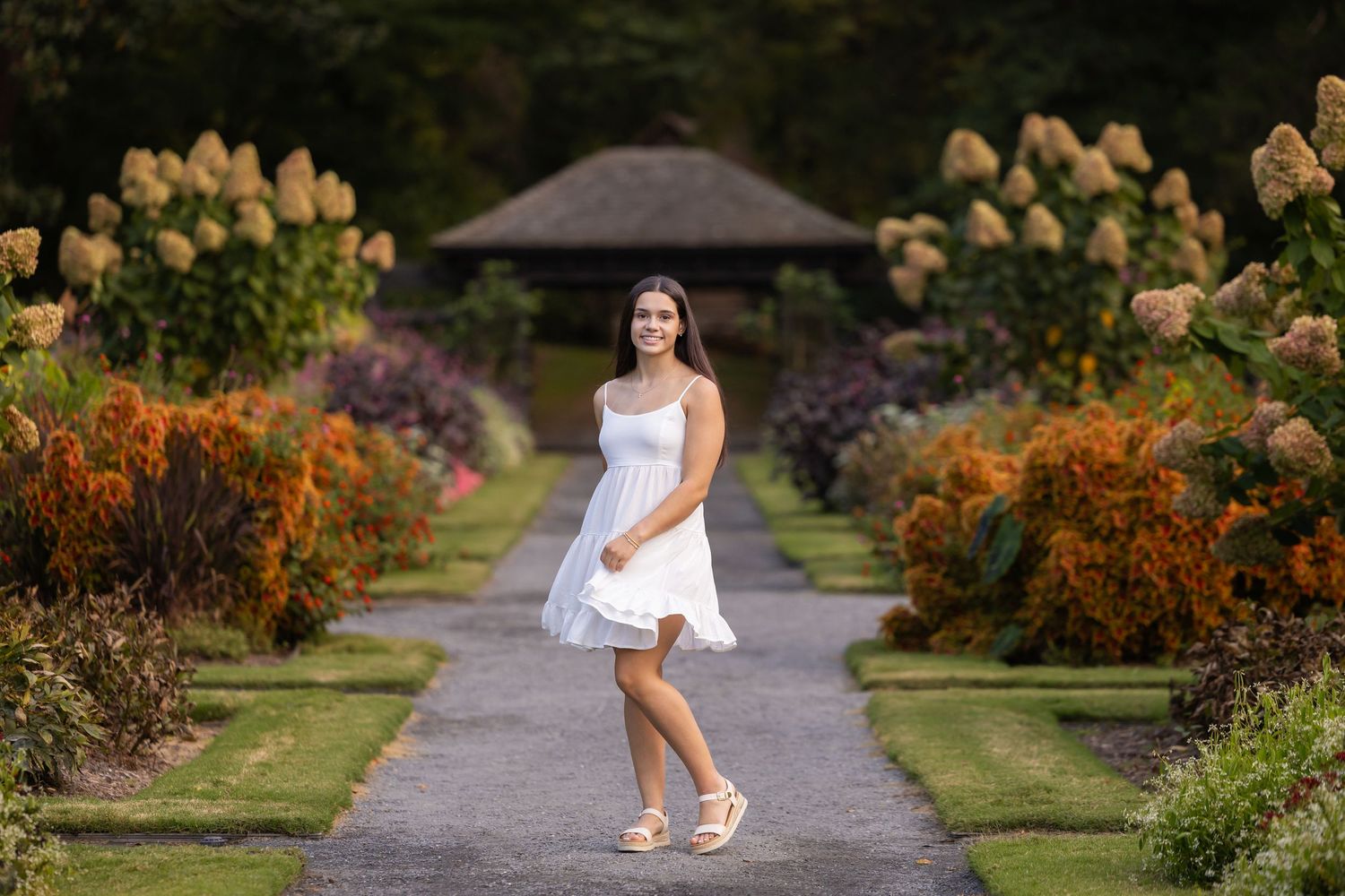 Woman in pink dress standing in blooming wildflower field during golden hour.