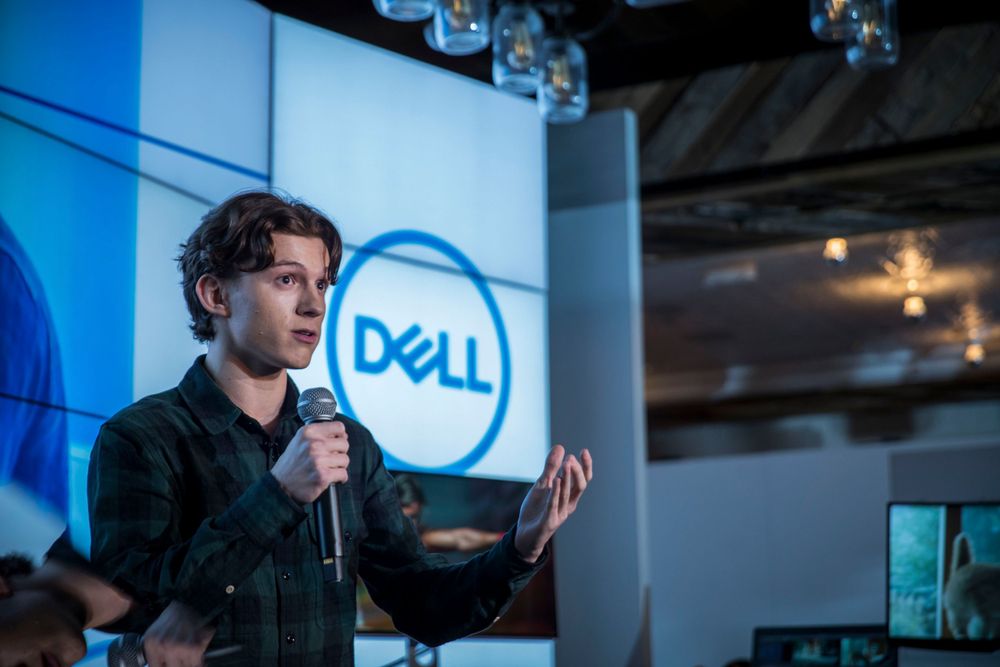 Speaker presenting on stage at Dell corporate event with blue lighting and company logo visible in background.