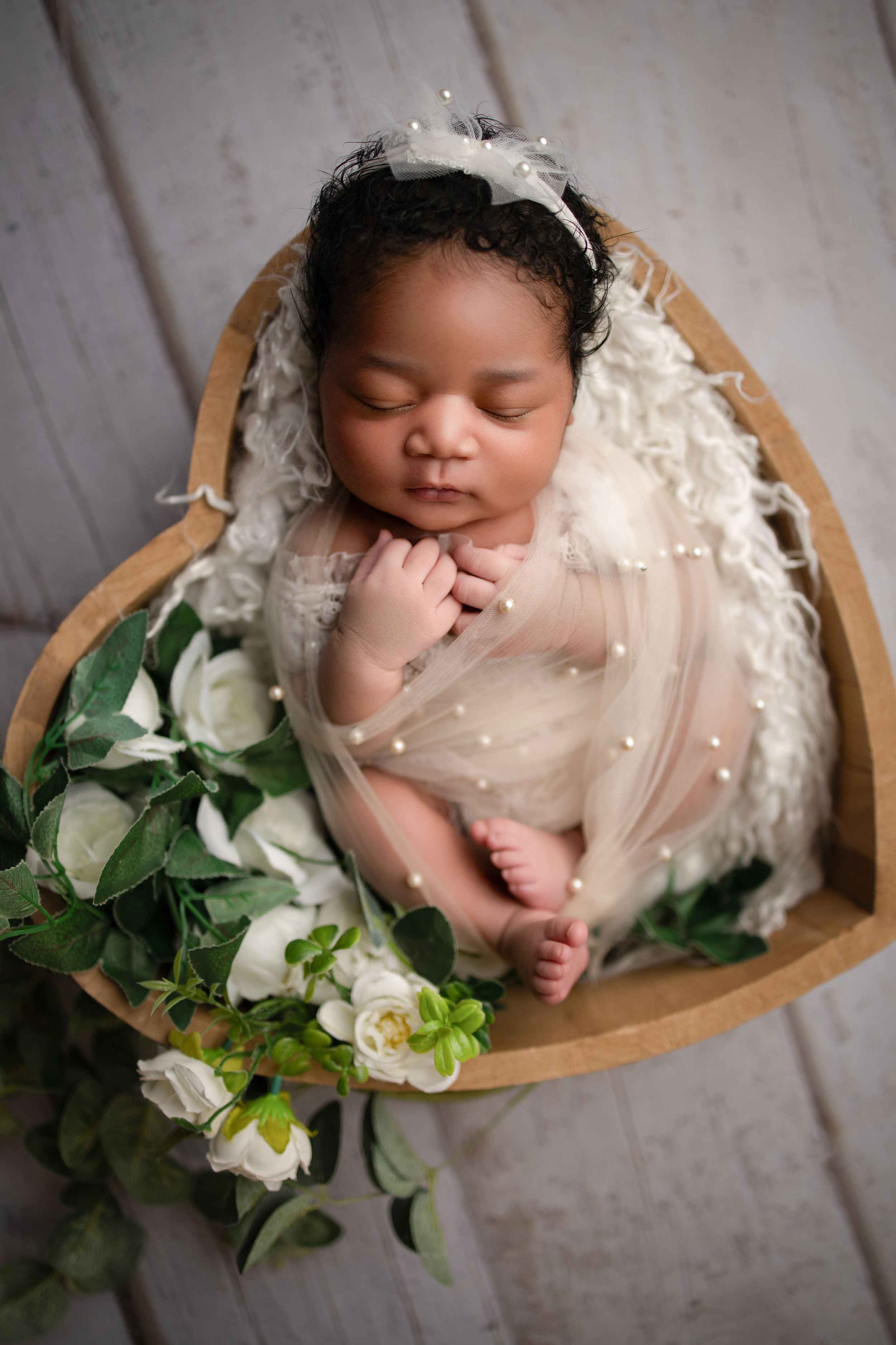 Luxury Newborn baby photoshoot, Vanessa Charlotte photography. Sleeping newborn in heart-shaped wooden bowl with lace wrap and white floral