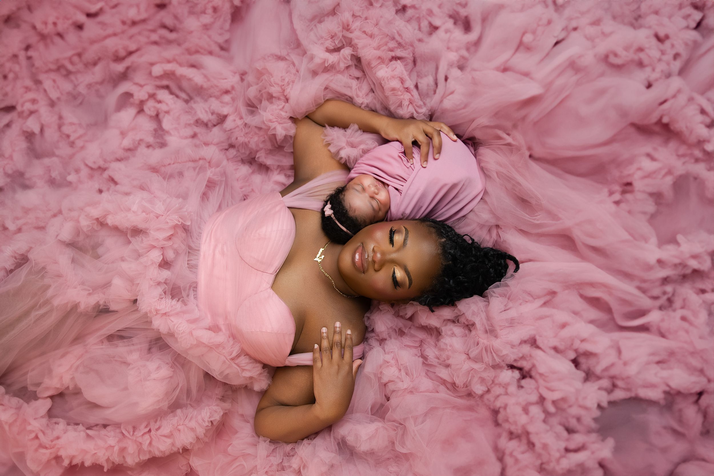 Person wearing a flowing pink tulle gown lies gracefully on a matching pink background Luxury Newborn baby photoshoot, Vanessa Charlotte