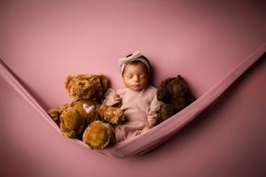A row of warm-toned photos showcase a sleeping baby nestled in a pink hammock with a teddy bear companion.