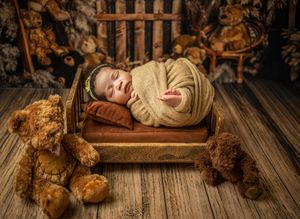 A sleeping baby lies on rustic wooden floor boards next to vintage teddy bears in warm sepia tones.