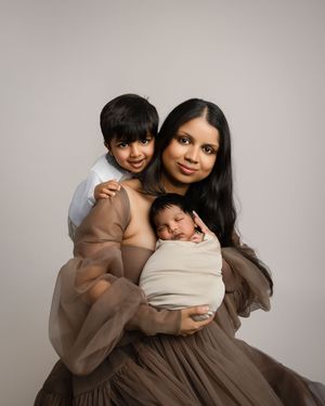 A family portrait in soft brown tones shows a mother and two children, with the baby wrapped in beige fabric.