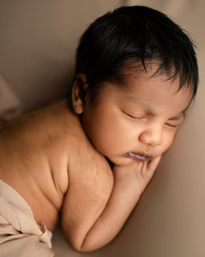 A peaceful sleeping newborn baby nestled in soft neutral tones during a professional portrait session.