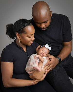 A tender family moment captured in black and white as parents cradle their newborn baby in matching black outfits.