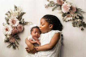 A serene newborn session featuring sweet moments with mother and child on a white backdrop with soft pink floral accents.