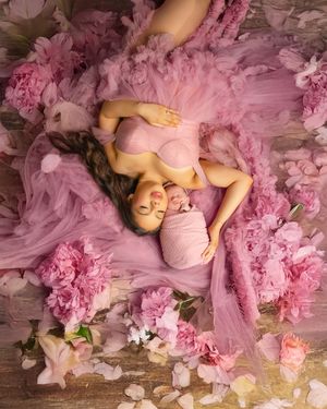 A dreamy portrait series featuring someone lying on a wooden floor surrounded by delicate pink flowers and tulle fabric.