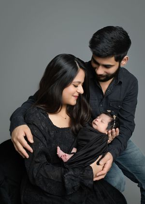 A couple in black and gray clothing embrace in a series of intimate poses against a neutral background.