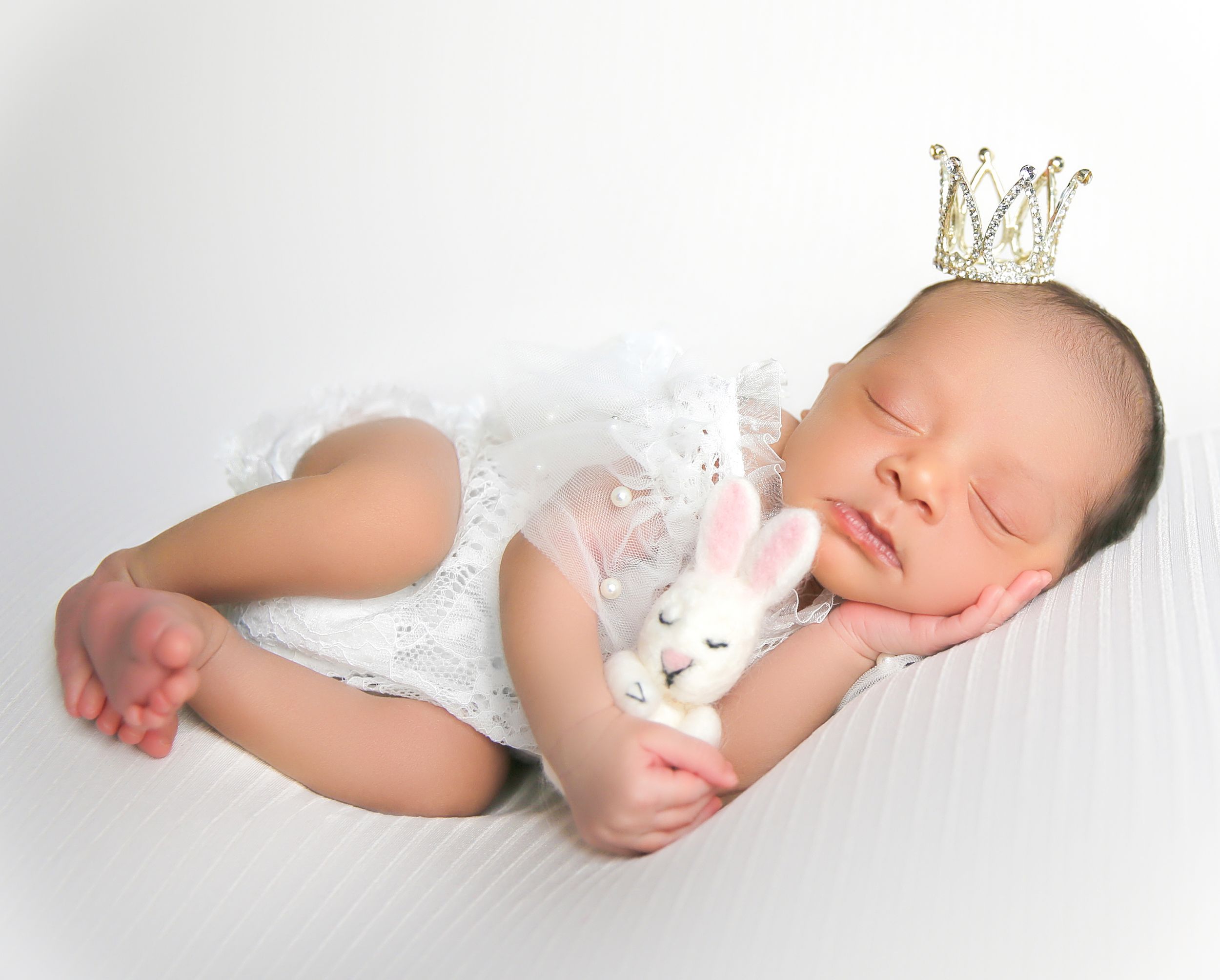 Luxury Newborn baby photoshoot, Vanessa Charlotte photography Sleeping newborn baby wearing white lace outfit and tiny crown lies peacefully