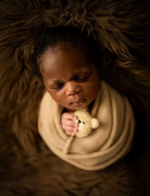 Artistic photography series showing sleeping subject in cream wrap against dark furry background.