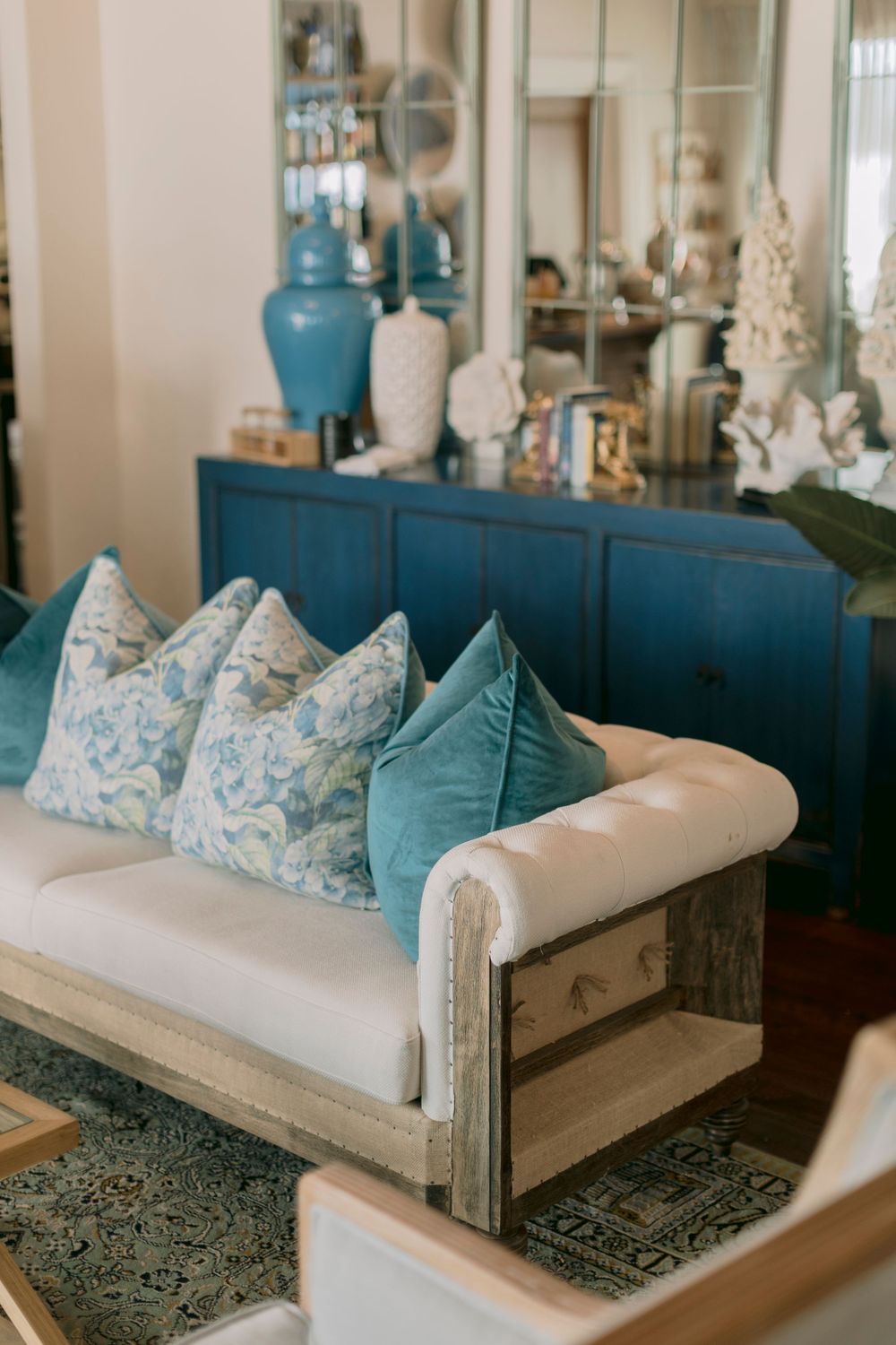 Rustic wooden sofa with blue and white patterned cushions against navy blue cabinet.