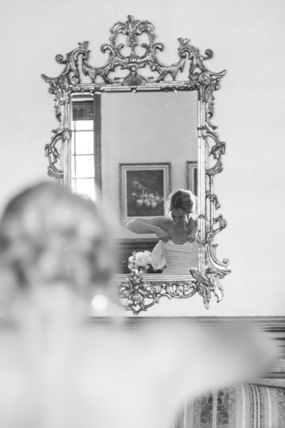 Ornate vintage mirror with baroque frame reflects an artistic black and white composition in interior setting.