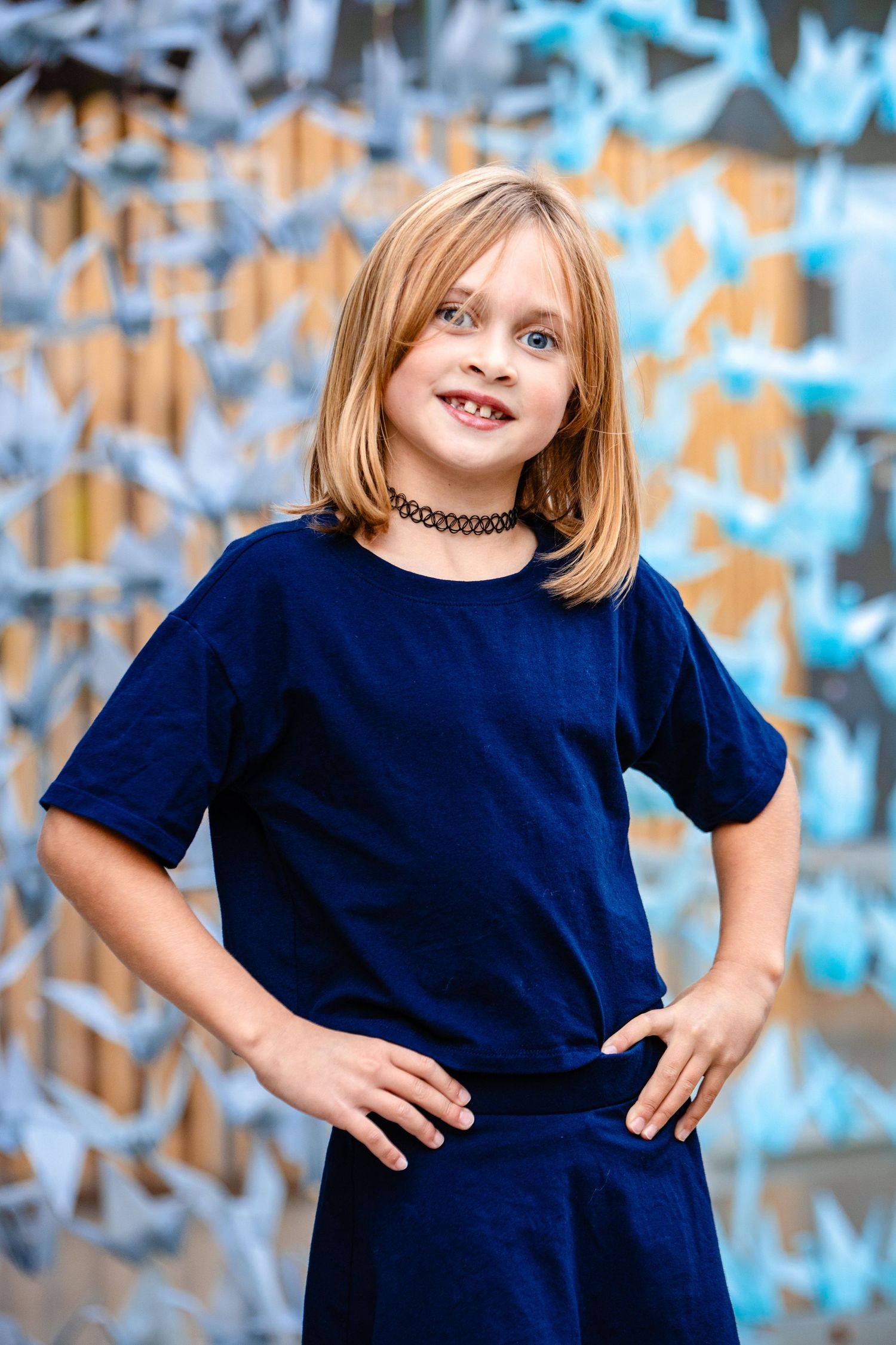 A child wearing a navy blue outfit poses confidently against a colorful graffiti wall background.