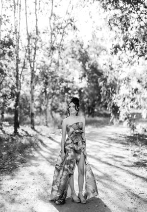Black and white photo of elegant dress silhouette against a wooded background.