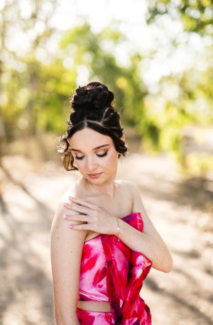 Close-up portrait showing elegant updo hairstyle and pink strapless dress in natural lighting.