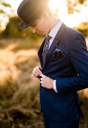 Detailed shot of navy suit jacket with coordinated tie and pocket square in golden afternoon light.