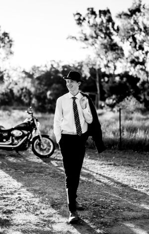 Noir-style monochrome photo of someone in business attire walking near a parked motorcycle.