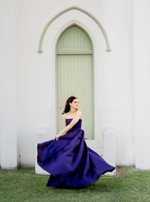 Elegant navy blue ball gown against white arched doorway with mint green door.