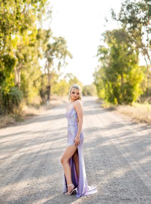 A lavender sequined formal dress in outdoor sunset photoshoot with elegant poses along a dirt path.