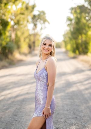 Sparkling lavender evening gown showcased on a golden-lit country road at sunset.