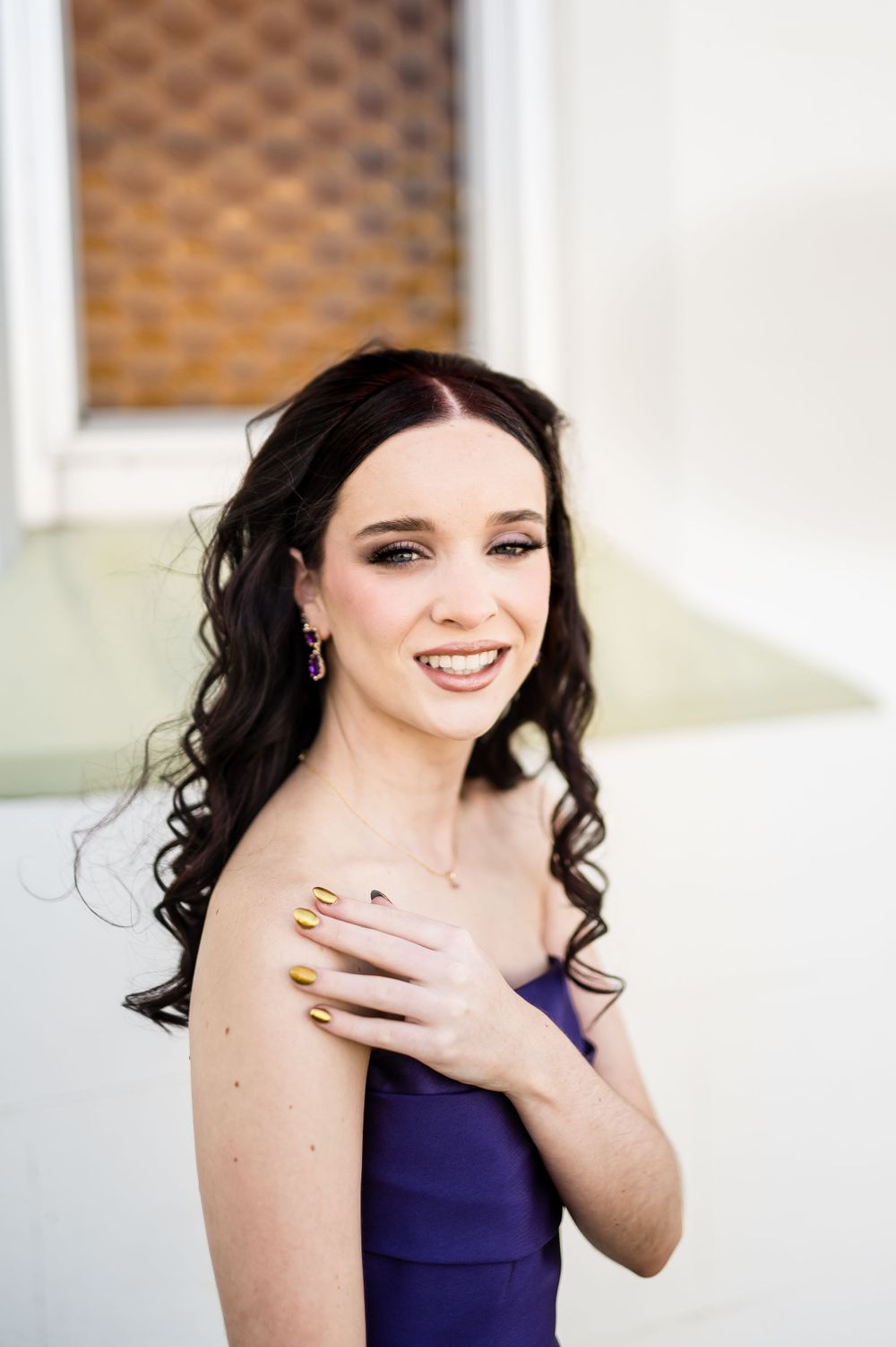 A navy blue formal dress worn in an elegant portrait series against a textured background.