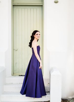 A sophisticated navy formal dress photographed in a series against white church architecture.