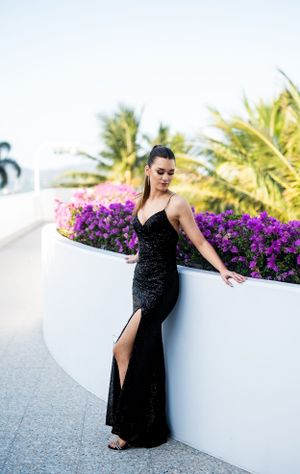 Glamorous evening wear session against white wall with purple flowers.