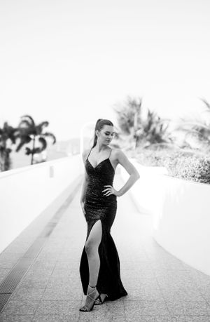 Black and white portrait showcasing an elegant evening gown on a modern walkway.