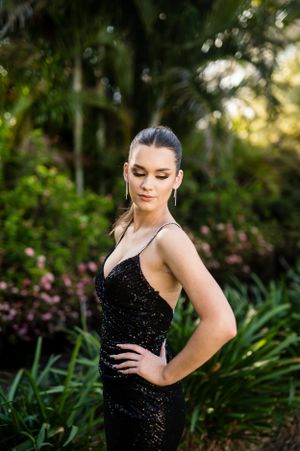 Evening photoshoot featuring a sequined black dress in a lush tropical garden setting.