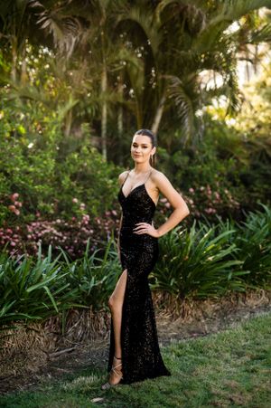 Elegant black sequin dress photoshoot in a lush garden setting during golden hour.