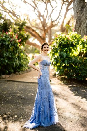 Stunning blue formal gown photographed in a series of poses along a garden walkway.