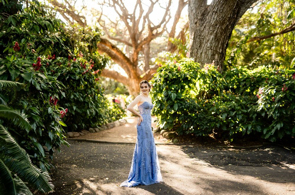 Garden pathway lined with trees and greenery featuring a blue formal dress.