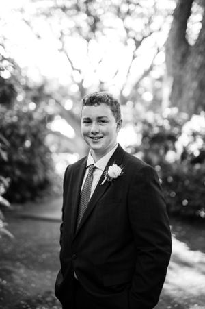 Black and white portrait showing formal attire on a sunlit garden path.