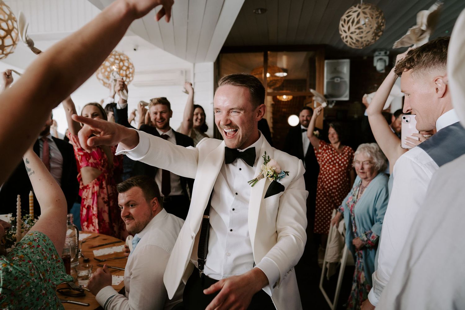 Wedding guests cheering Bride and grooms entrance to wedding breakfast at tunnels beach wedding venue in north devon