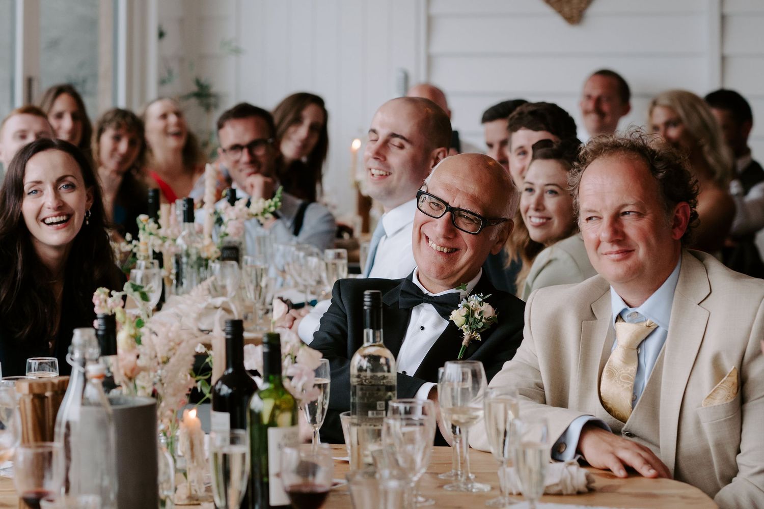 wedding guests laughing during speeches at Tunnels Beach wedding venue in north devon