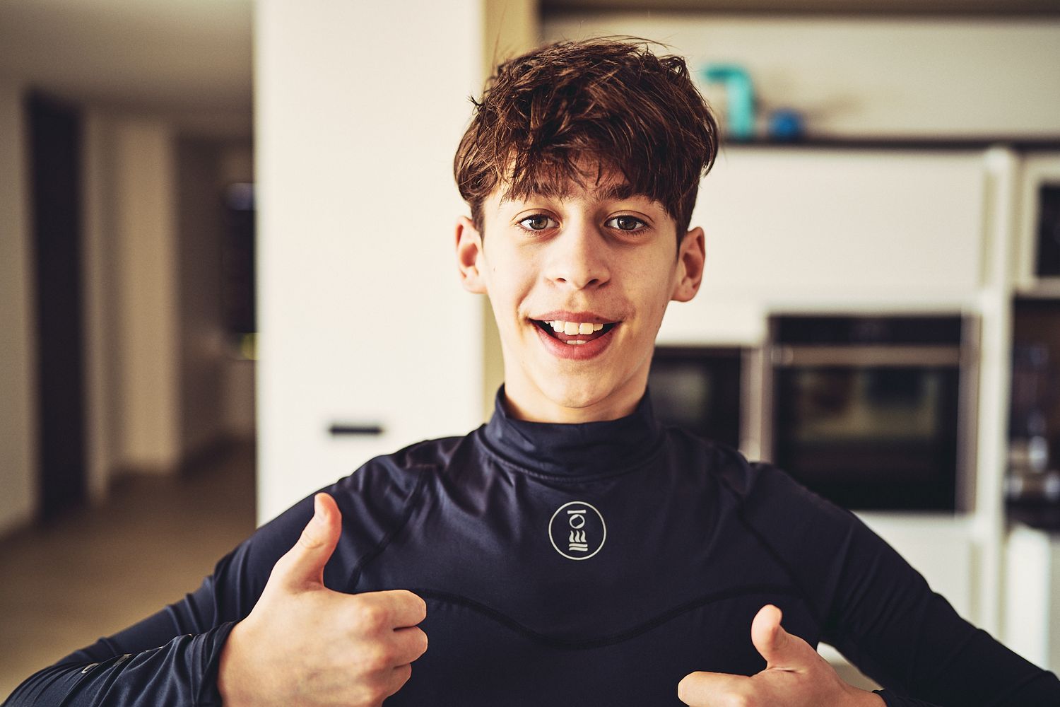 Person in black turtleneck giving thumbs up while smiling at camera.