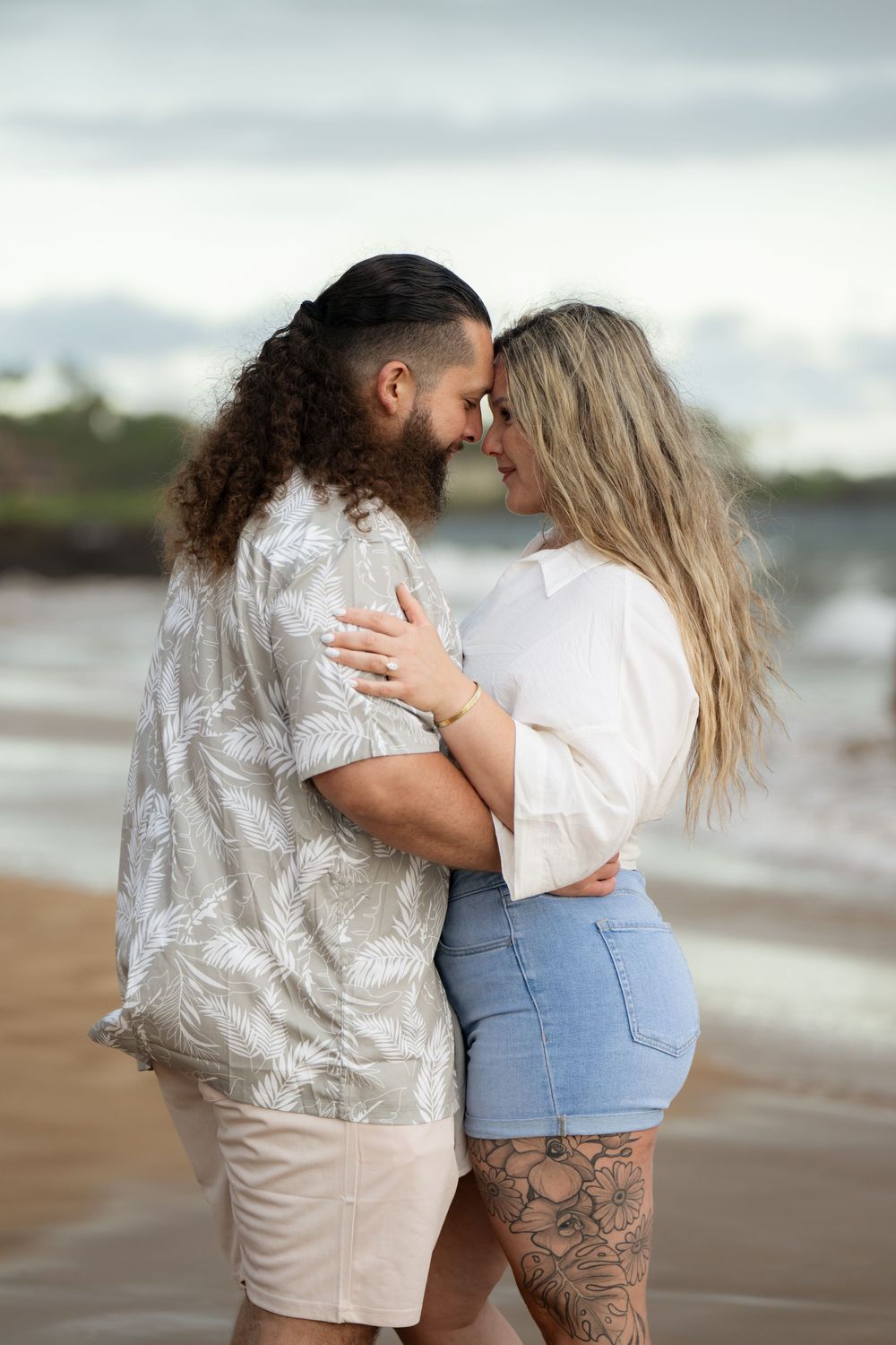 Intimate beach portrait of couple in casual wear sharing a romantic moment by the ocean.