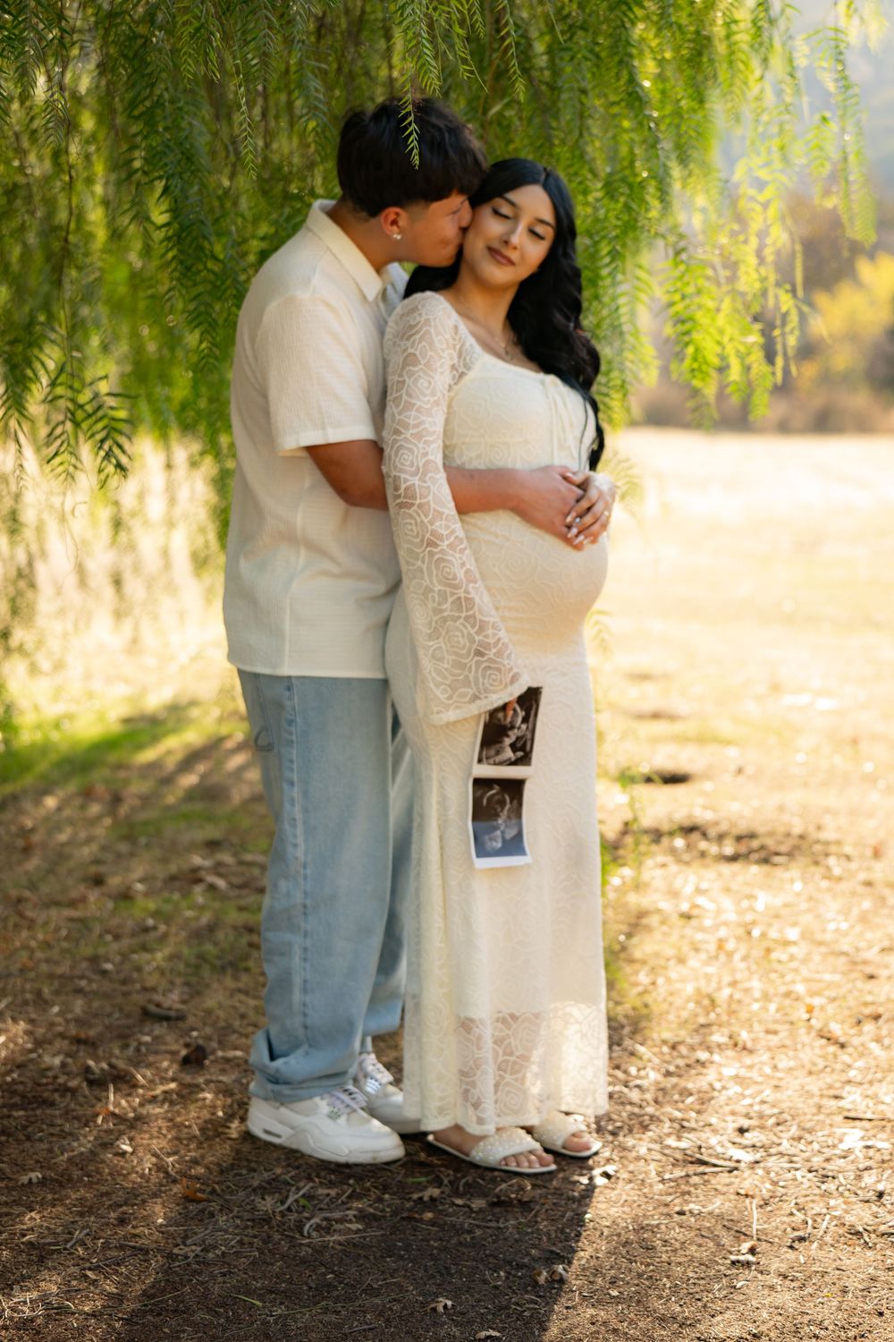 Romantic couple portraits under a weeping willow tree in soft natural lighting.