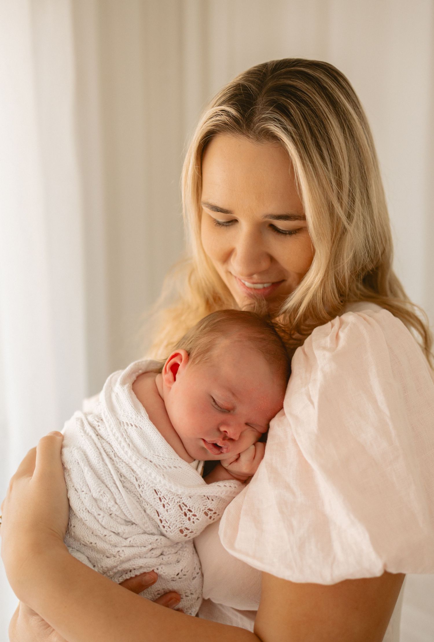 A tender moment shows a parent in white holding a sleeping baby in an intimate portrait sequence.