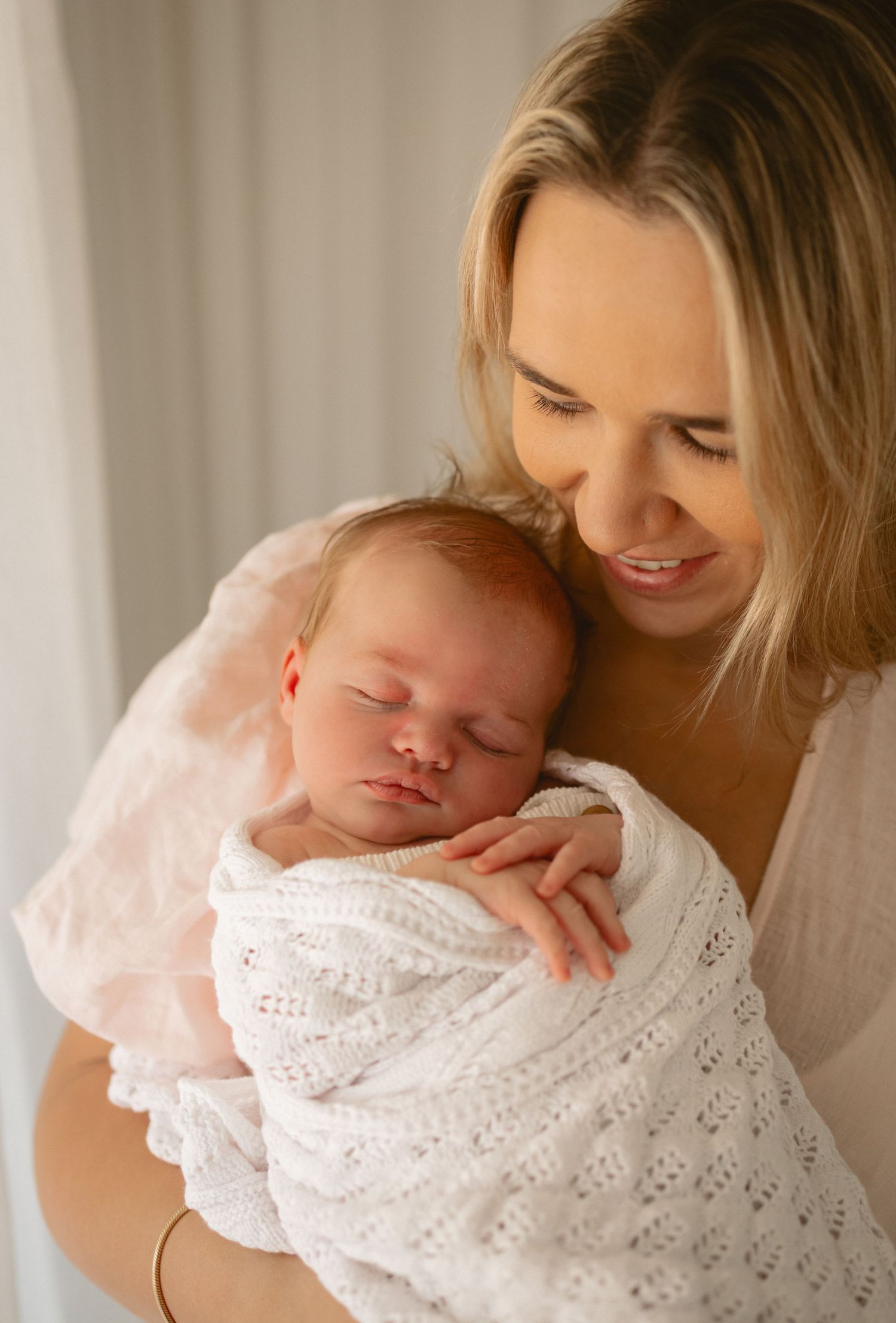 A peaceful series of photos showing a sleeping newborn in white lacy clothing being cradled gently.