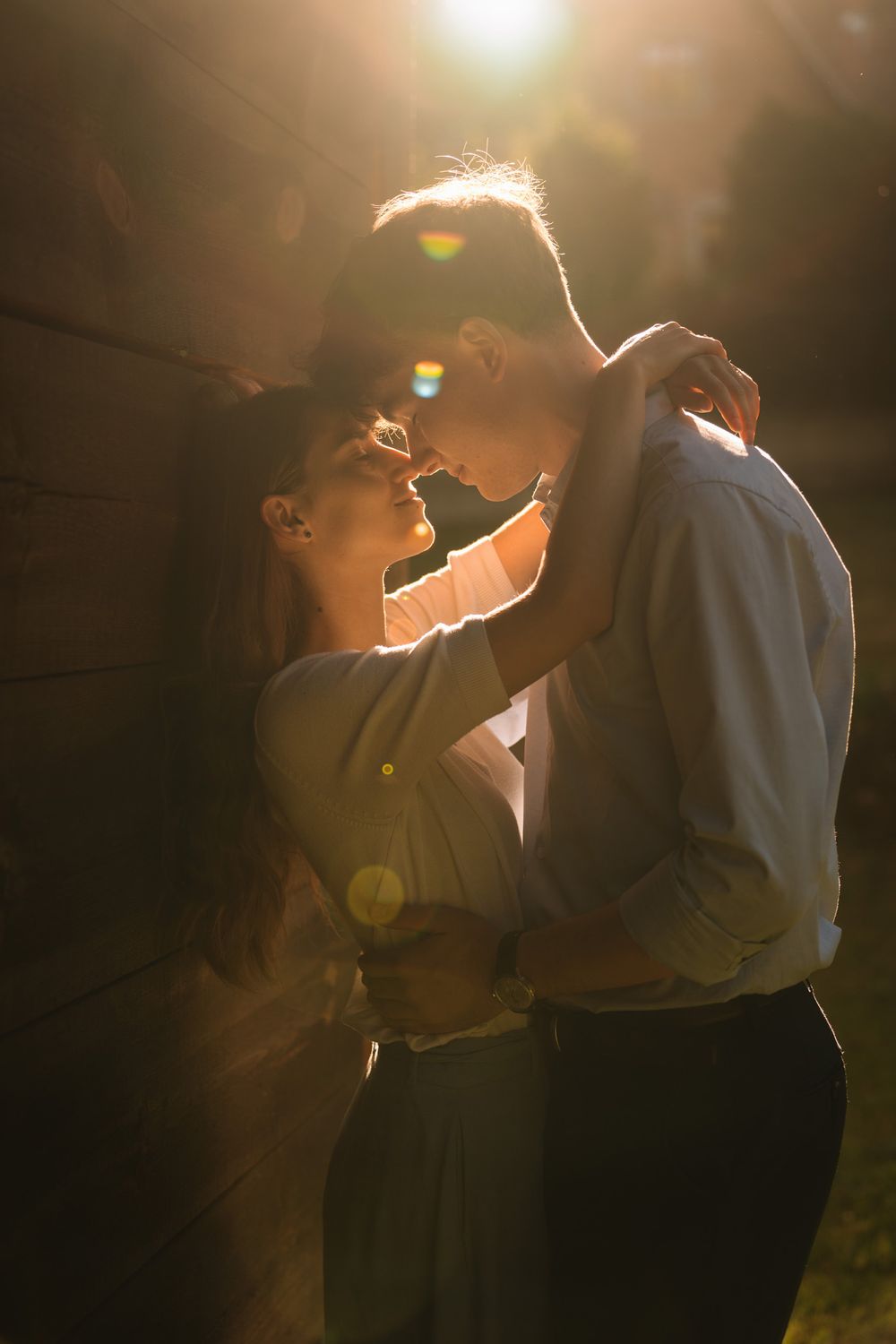 A couple dances together in warm sunlit ambiance with romantic lens flare effects creating a dreamy atmosphere.