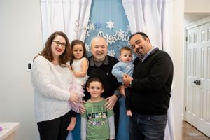 A family poses together against a white wall with blue decorative text in their home interior.