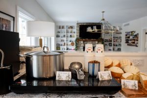 Coffee service station with stainless steel appliances and storage shelves in a bright white kitchen interior.