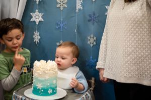 A beautiful blue ombre winter birthday cake is displayed with hanging paper snowflakes in the background.